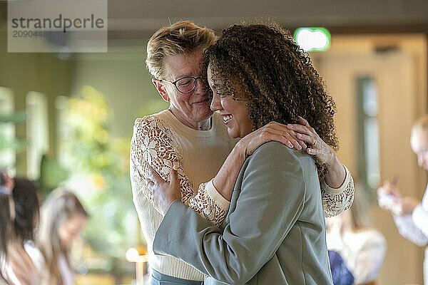 Joyful embrace between two women sharing a moment of happiness and affection indoors.