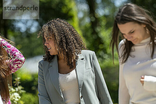 Three women enjoying a sunny day outdoors  laughing and walking together in casual fashion.