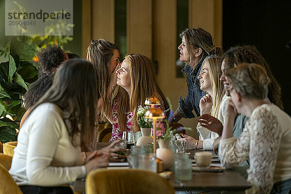 A group of women engaged in conversation at a cozy caf? with drinks on the table.