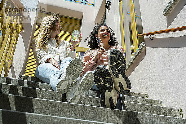 Two friends enjoying ice cream on sunny stairs  smiling and relaxing.