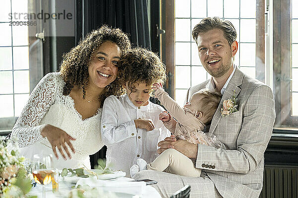 A happy family dressed in formal attire celebrating a special occasion at a table adorned with flowers.