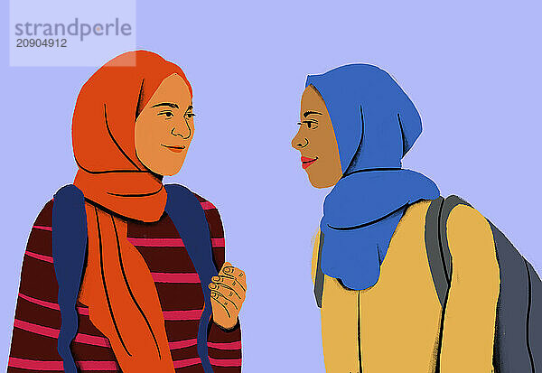 Two women wearing colorful hijabs are engaged in a conversation  smiling at each other against a purple background.