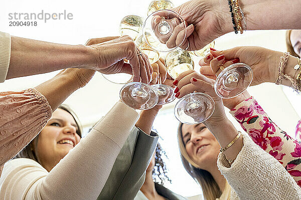 Group of people toasting with champagne glasses from an underneath perspective  celebrating a special occasion.