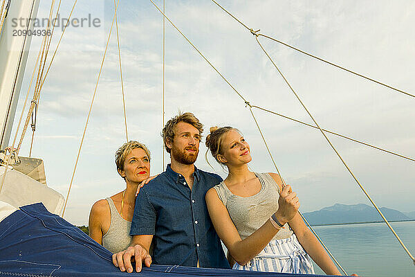 Three individuals are enjoying a serene boat ride with a view of the open sky and calm waters during sunset.