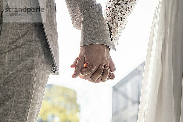 A close-up of a man and woman holding hands  symbolizing companionship with a focus on the interlocked fingers  set against a softly blurred background.