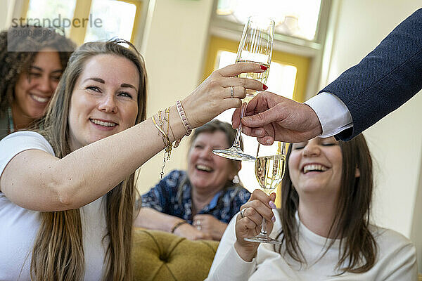 Friends cheerfully toasting with champagne glasses during a celebration indoors  with joyful expressions.