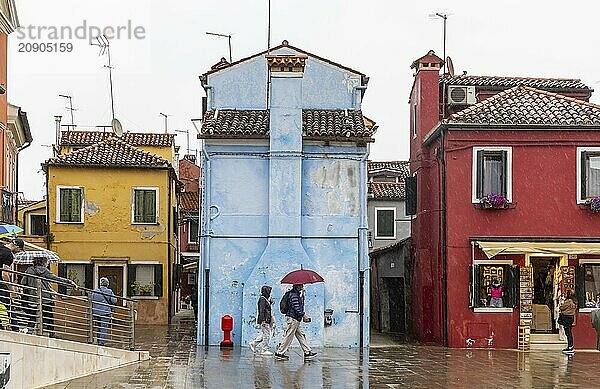 Stadtansicht von Burano mit bunt bemalten Häusern und Kanälen. Regenwetter  die Menschen haben Schirme bei sich. Burano  Venedig  Venezien  Italien  Europa