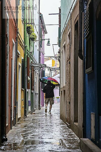 Stadtansicht von Burano mit bunt bemalten Häusern und Kanälen. Regenwetter  die Menschen haben Schirme bei sich. Burano  Venedig  Venezien  Italien  Europa