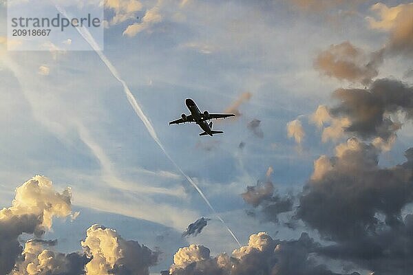 Wolken am Himmel  Silhouette eines Flugzeugs beim Start. Dramatische Wolkenstimmung kurz vor Sonnenaufgang. Zürich  Schweiz  Europa