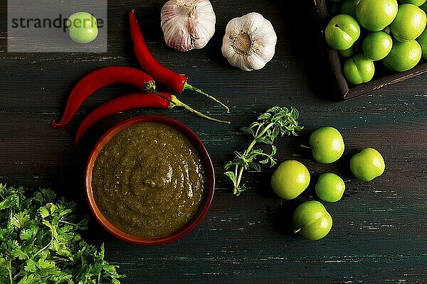 Tkemali Sauce  traditionelle georgische Küche  grüne Kirschpflaume  mit Zutaten für die Sauce  Koriander  Minze  scharfer Pfeffer  Knoblauch  auf einem Holztisch  Nahaufnahme  rustikal  Lebensmittel Hintergrund  keine Menschen  selektiver Fokus  Sauce  grüne Sauce  tkemali  georgische Küche  hausgemacht