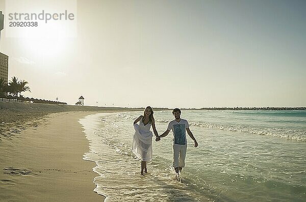 Paar von Liebenden zu Fuß Hand in Hand auf karibischen Strand bei Sonnenuntergang