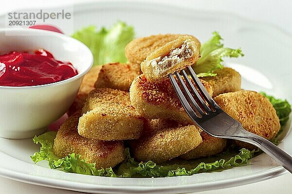 Gebratene Hähnchenbrust Nuggets  auf Salatblättern  mit Tomatensauce  horizontal  ohne Personen  selektiver Fokus