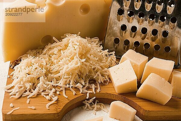 Grated cheese  Maasdam  on a cutting board  grater and cheese knife  close-up  no people