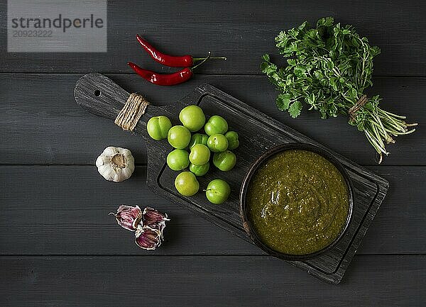 Tkemali Sauce  traditionelle georgische Küche  grüne Kirschpflaume  mit Zutaten für die Sauce  Koriander  Minze  scharfer Pfeffer  Knoblauch  auf einem Holztisch  Nahaufnahme  rustikal  Lebensmittel Hintergrund  keine Menschen  selektiver Fokus  Sauce  grüne Sauce  tkemali  georgische Küche  hausgemacht