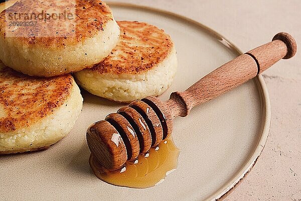 Hüttenkäsepfannkuchen  mit Honig  Nahaufnahme  auf einem beigen Tisch  selektiver Fokus  keine Personen