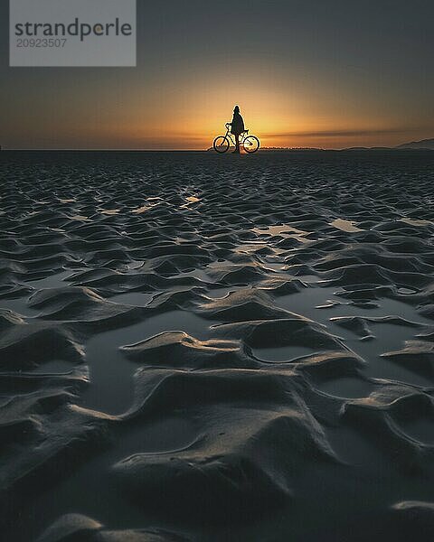 Silhouette of a person with a bicycle on a beach during a picturesque sunset  Tofino  BC  Canada  North America