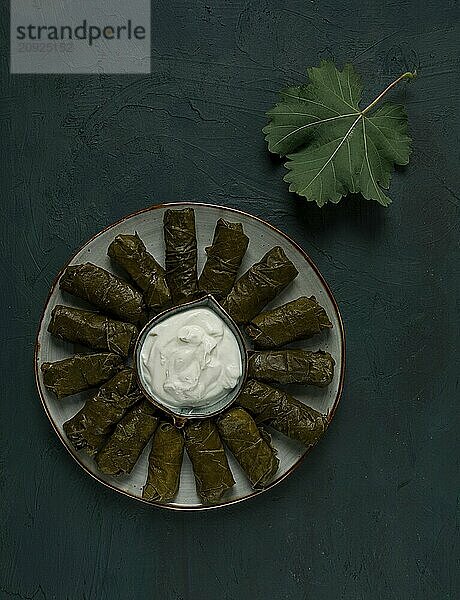 Dolma  Kohlrouladen in Traubenblättern  traditionelles armenisches Gericht  mit weißer Soße  Draufsicht  Nahaufnahme  selektiver Fokus