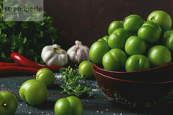 Tkemali  grüne Kirschpflaume  mit Zutaten für Sauce  Koriander  Minze  Paprika  Knoblauch  auf einem Holztisch  Nahaufnahme  rustikal  Lebensmittel Hintergrund  keine Menschen  selektiver Fokus