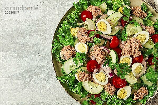 Thunfischsalat  Gemüsesalat mit Wachteleiern  Kopfsalat  roten Zwiebeln und Gurken  auf einem hellgrauen Tisch  Keto Food  Lifestyle  gesunde Ernährung  selektiver Fokus  Draufsicht  keine Menschen