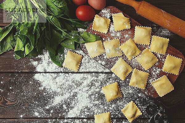 Käse Ravioli  mit Spinat und Käse  mit Zutaten  auf einem Holztisch  horizontal  keine Personen  selektiver Fokus