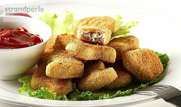 Gebratene Hähnchenbrust Nuggets  auf Salatblättern  mit Tomatensauce  horizontal  ohne Personen  selektiver Fokus