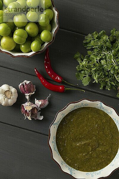 Tkemali Sauce  traditionelle georgische Küche  grüne Kirschpflaume  mit Zutaten für die Sauce  Koriander  Minze  scharfer Pfeffer  Knoblauch  auf einem Holztisch  Nahaufnahme  rustikal  Lebensmittel Hintergrund  keine Menschen  selektiver Fokus  Sauce  grüne Sauce  tkemali  georgische Küche  hausgemacht