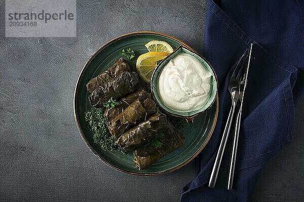 Dolma  Kohlrouladen  Traubenblätter mit Füllung  weiße Soße  Zitrone und Kräuter  rustikal  selektiver Fokus  keine Menschen