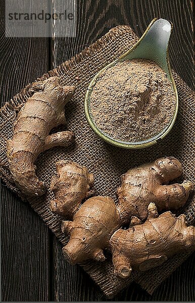 Gemahlene und frische Ingwerwurzel  auf einem Holztisch  rustikaler Stil  selektiver Fokus  keine Personen