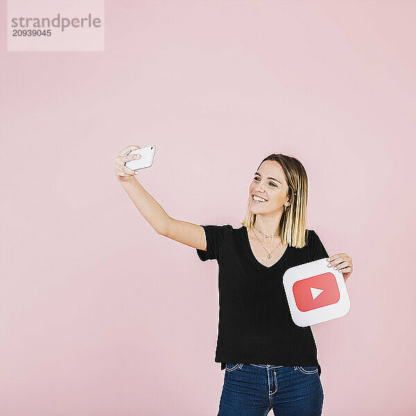 Glückliche Frau mit Spielsymbol  die ein Selfie mit ihrem Handy macht