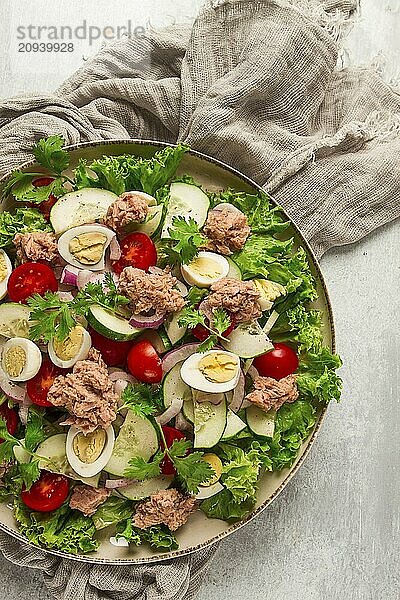 Thunfischsalat  Gemüsesalat mit Wachteleiern  Kopfsalat  roten Zwiebeln und Gurken  auf einem hellgrauen Tisch  Keto Food  Lifestyle  gesunde Ernährung  selektiver Fokus  Draufsicht  keine Menschen