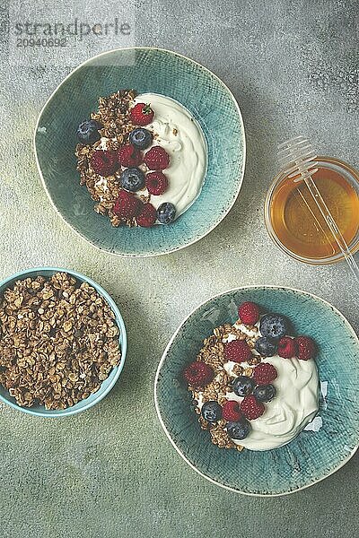 Breakfast  two bowls  yogurt  muesli with berries  and honey  homemade  no people