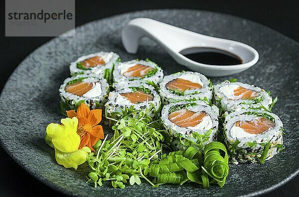 Perfektes Sushi  traditionelle japanische Küche. Köstliche Uramaki mit Shoyo Sauce auf dem dekorierten Teller  schwarzer Hintergrund