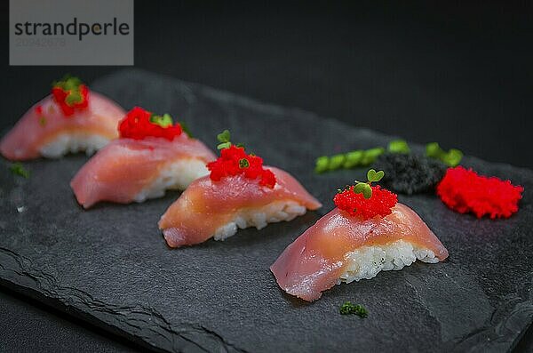 Perfektes Sushi  traditionelle japanische Küche. Köstlicher Thunfisch Kiguiri mit Capellin Rogen (Kaviar) auf dem dekorierten Teller  schwarzer Hintergrund