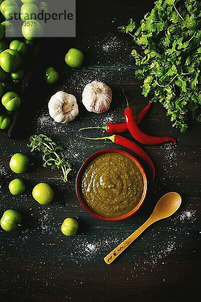 Tkemali Sauce  traditionelle georgische Küche  grüne Kirschpflaume  mit Zutaten für die Sauce  Koriander  Minze  scharfer Pfeffer  Knoblauch  auf einem Holztisch  Nahaufnahme  rustikal  Lebensmittel Hintergrund  keine Menschen  selektiver Fokus  Sauce  grüne Sauce  tkemali  georgische Küche  hausgemacht