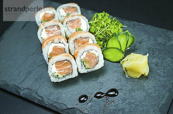 Sushi  traditionelle japanische Küche. Leckeres Uramaki auf dekoriertem Teller  schwarzer Hintergrund