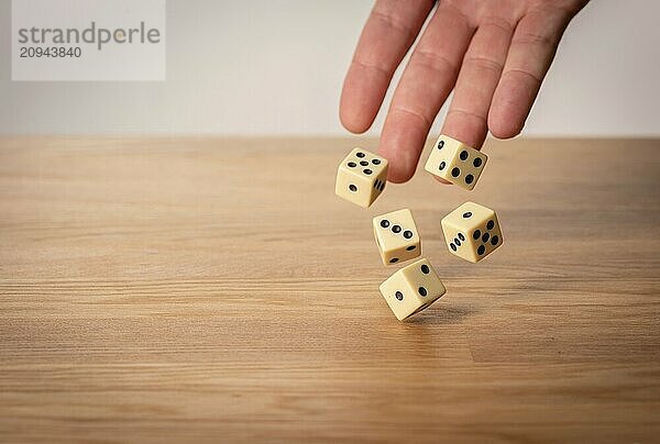 Eine Hand wirft Würfel vor einem dunklen Hintergrund