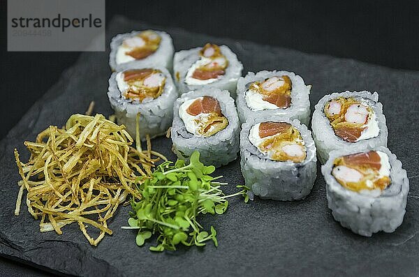 Sushi  traditionelle japanische Küche. Leckeres Uramaki auf dekoriertem Teller  schwarzer Hintergrund