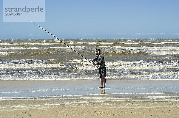 Junger Mann beim Angeln am Strand  Sportfischen