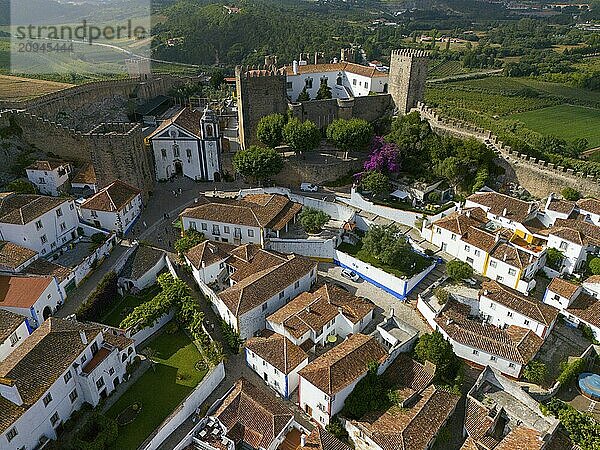 Luftaufnahme einer mittelalterlichen Stadt mit weißen Häusern und roten Ziegeldächern  umgeben von Stadtmauern und grüner Landschaft  Stadt  Burg  Castelo de Óbidos  Stadtmauer  Óbidos  Obidos  Oeste  Centro  Estremadura  Portugal  Europa