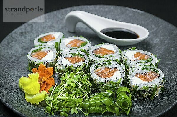 Perfektes Sushi  traditionelle japanische Küche. Köstliche Uramaki mit Shoyo Sauce auf dem dekorierten Teller  schwarzer Hintergrund