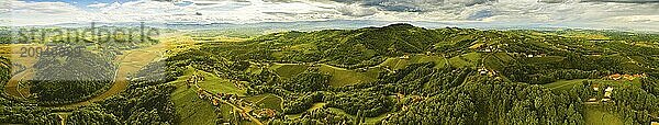 Luftbildpanorama von grünen Hügeln und Weinbergen mit Bergen im Hintergrund. Österreich Weinberge Landschaft. Leibnitz Gebiet in der Südsteiermark  Weinland. Toskana wie Ort und berühmter Touristenort