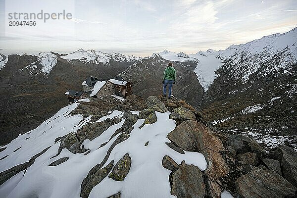 Bergsteigerin blickt auf Bergpanorama und Gletscher  Berghütte Ramolhaus im Herbst mit Schnee  bei Sonnenuntergang  Blick auf Gurgler Ferner mit Gipfel Hochwilde und Falschungsspitze  Ötztaler Alpen  Tirol  Österreich  Europa