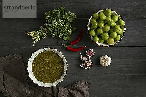 Tkemali Sauce  traditionelle georgische Küche  grüne Kirschpflaume  mit Zutaten für die Sauce  Koriander  Minze  scharfer Pfeffer  Knoblauch  auf einem Holztisch  Nahaufnahme  rustikal  Lebensmittel Hintergrund  keine Menschen  selektiver Fokus  Sauce  grüne Sauce  tkemali  georgische Küche  hausgemacht