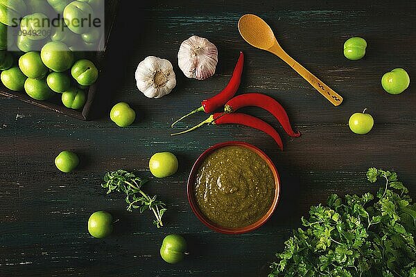 Tkemali Sauce  traditionelle georgische Küche  grüne Kirschpflaume  mit Zutaten für die Sauce  Koriander  Minze  scharfer Pfeffer  Knoblauch  auf einem Holztisch  Nahaufnahme  rustikal  Lebensmittel Hintergrund  keine Menschen  selektiver Fokus  Sauce  grüne Sauce  tkemali  georgische Küche  hausgemacht