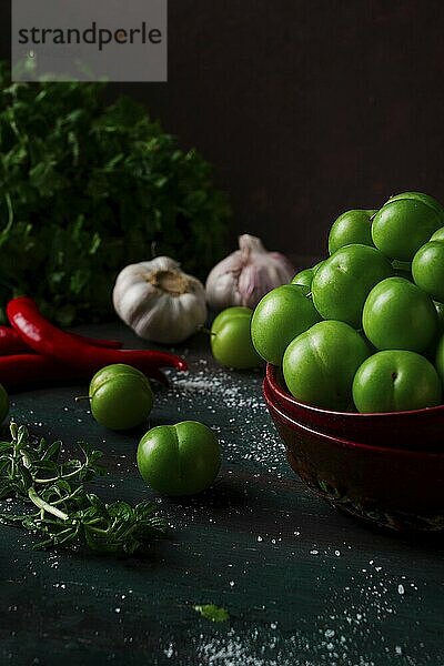 Tkemali  grüne Kirschpflaume  mit Zutaten für Sauce  Koriander  Minze  Paprika  Knoblauch  auf einem Holztisch  Nahaufnahme  rustikal  Lebensmittel Hintergrund  keine Menschen  selektiver Fokus