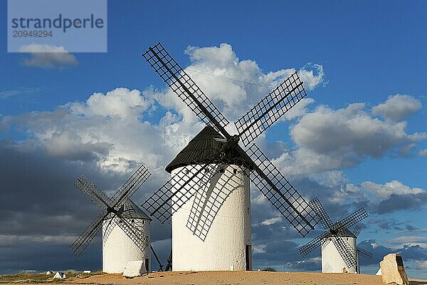 Drei Windmühlen stehen in einer offenen Landschaft unter einem bewölkten  aber sonnigen Himmel  Windmühlen  Campo de Criptana  Provinz Ciudad Real  Kastilien-La Mancha  Route des Don Quijote  Spanien  Europa