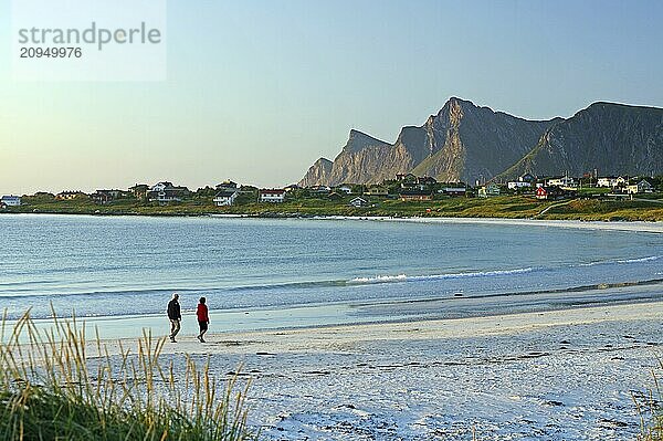 Zwei Personen an einem langem  weissen Sandstrand  Berge und ein kleines Dorf  Ramberg  Flakstad  Lofoten  Nordland  Norwegen  Europa