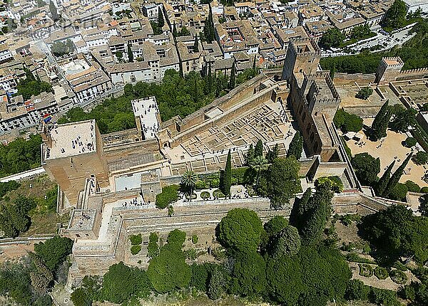 Luftaufnahme eines Schlosses mit umgebenden Mauern und Gebäuden  eingebettet in eine grüne Umgebung mit Stadt im Hintergrund  Luftaufnahme  Alhambra  Andalusien  Granada  Spanien  Europa