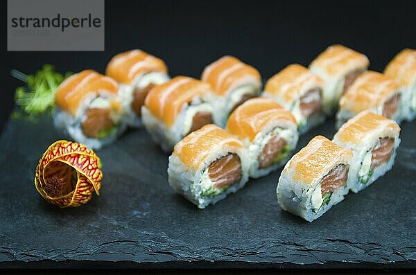 Sushi  traditionelle japanische Küche. Leckeres Uramaki auf dekoriertem Teller  schwarzer Hintergrund