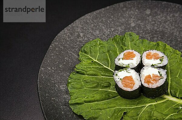 Perfektes Sushi  traditionelle japanische Küche. Leckere Hossomaki auf dem dekorierten Teller  schwarzer Hintergrund